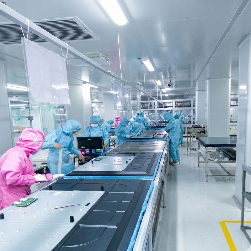 Línea de producción de pantallas interactivas Computerland con técnicos ensamblando equipos